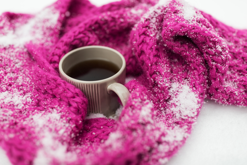 close up of tea or coffee and winter scarf in snow